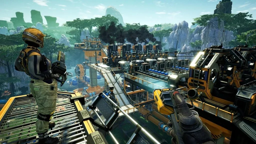 A screenshot from Satisfactory, showing a player character in a futuristic suit overlooking a massive, complex factory built within a lush, alien landscape. The factory features numerous automated machines, conveyor belts, and pipes, with smoke rising from some structures.